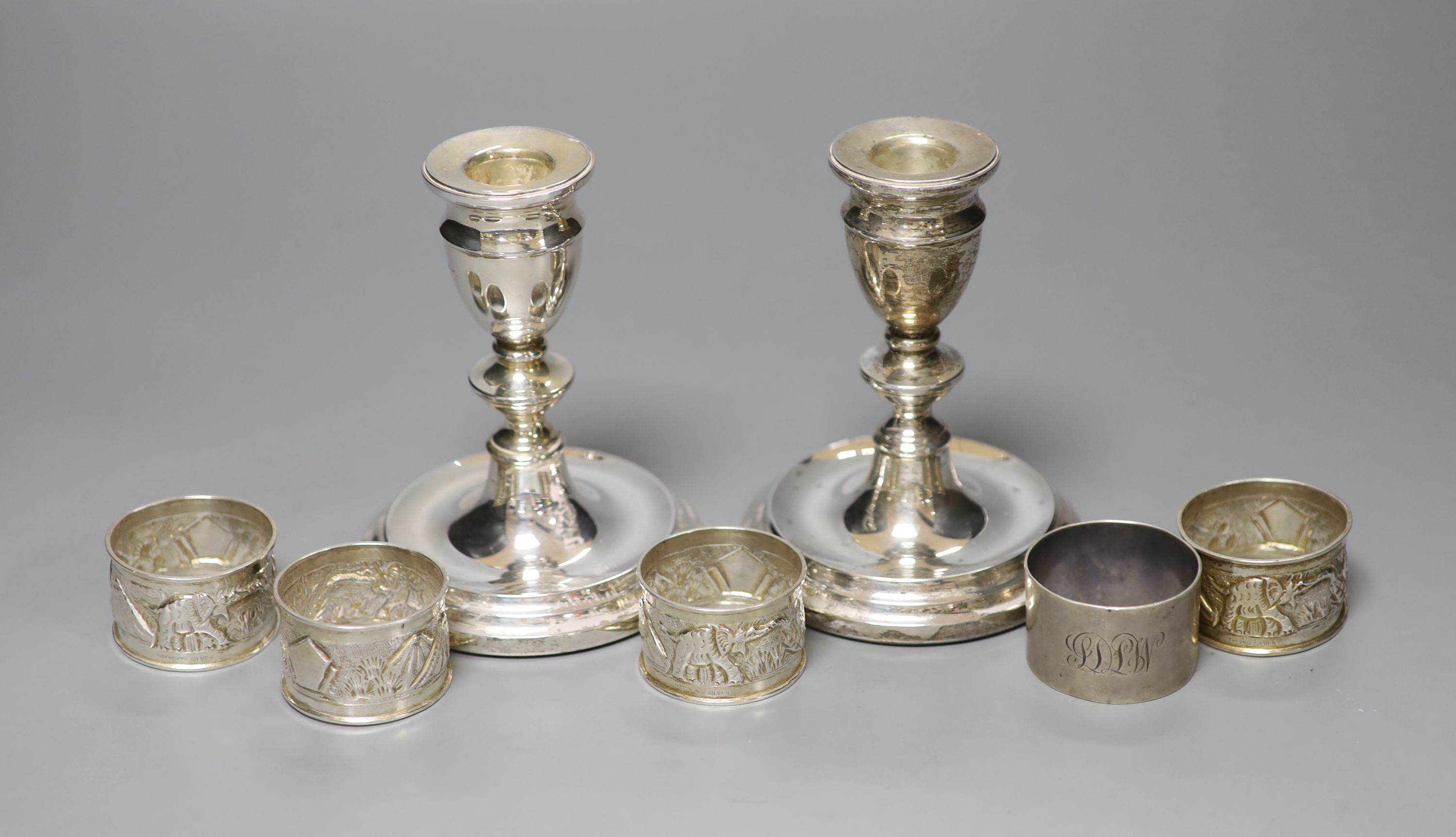 A pair of modern silver dwarf candlesticks, 12cm, a silver napkin ring and four sterling napkin rings.